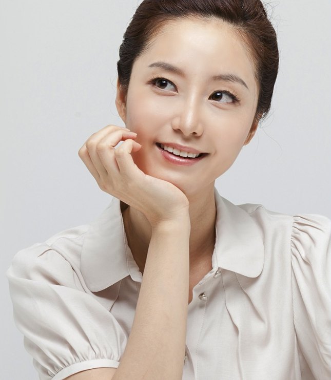 손으로 턱을 받치고 미소 짓는 여성 모델의 상반신 사진