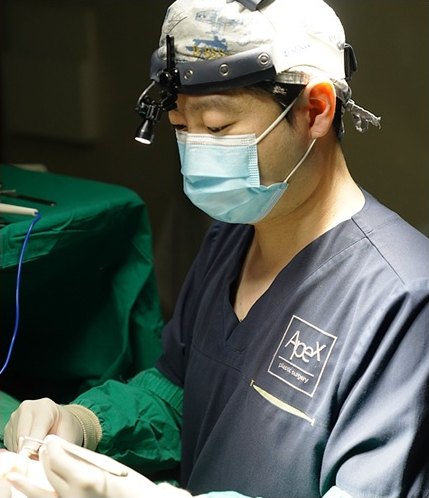 수술실에서 확대경과 헤드라이트를 착용하고 집도 중인 에이펙스성형외과 의료진