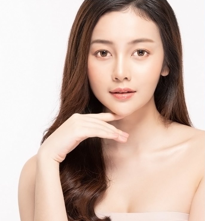 긴 웨이브 머리의 여성 모델이 손끝을 턱에 대고 정면을 바라보는 모습