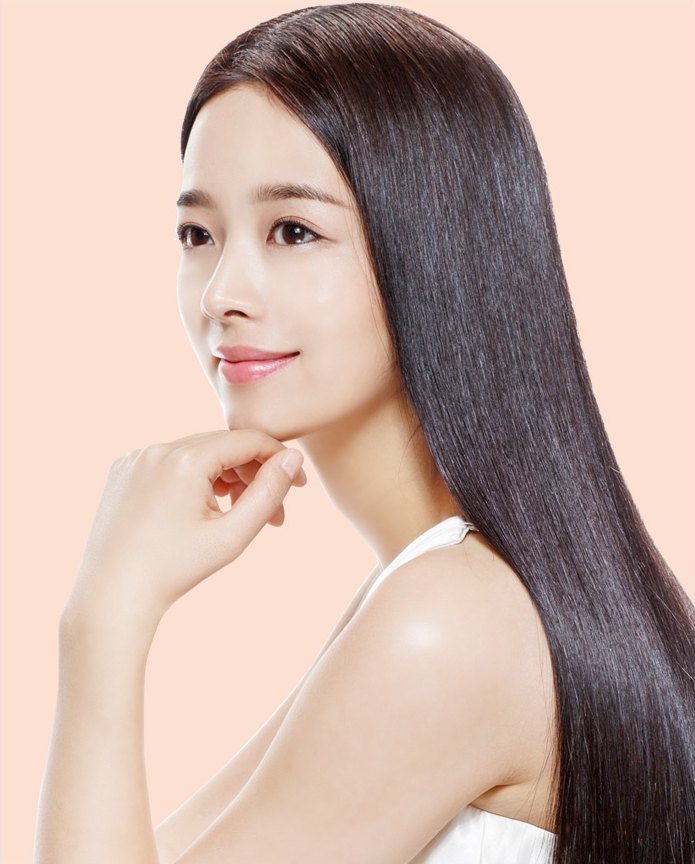 긴 생머리의 여성이 손끝을 턱에 대고 먼 곳을 바라보는 모습
