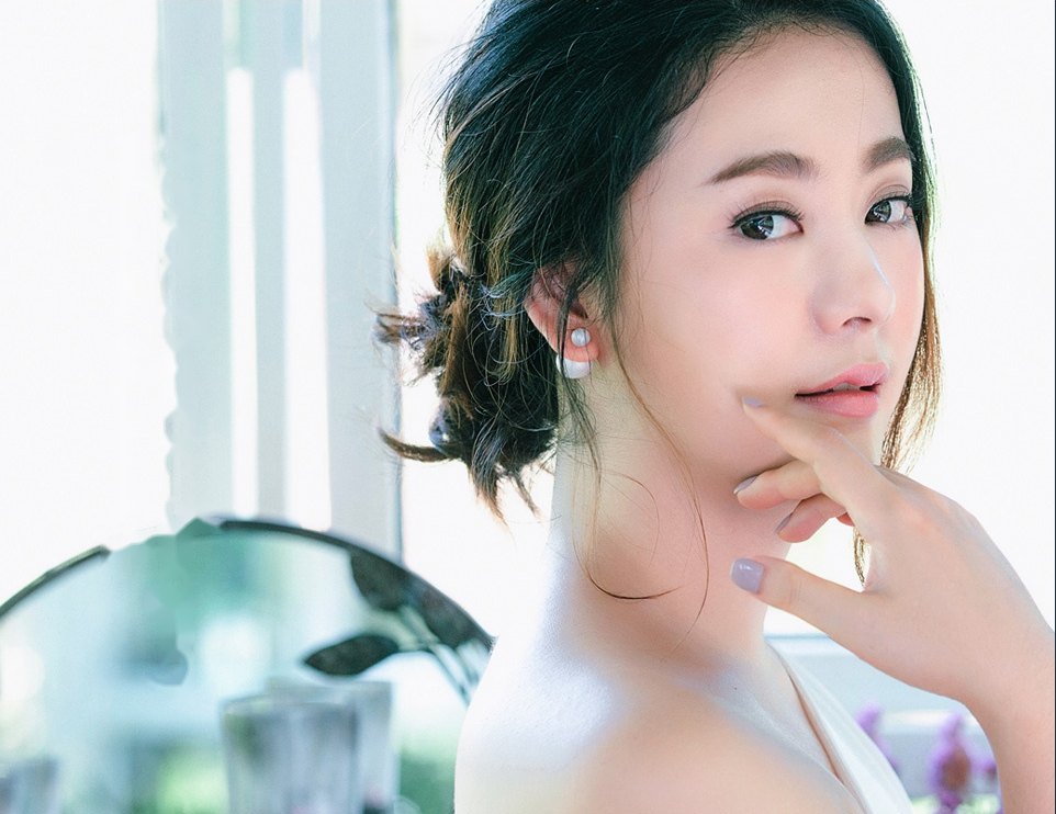올림머리를 한 여성이 손끝을 턱에 대고 바라보는 모습