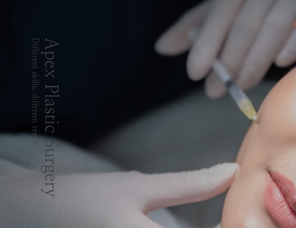 장갑을 낀 손이 얼굴에 윤곽주사를 놓는 시술 장면. 사진에는 원본 워터마크 'Apex Plastic Surgery — Different skills, different result' 가 세로로 새겨져 있다.