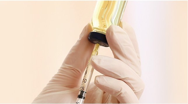 장갑 낀 손이 유리 앰플에서 주사기로 물광주사 약물을 뽑아 올리는 장면