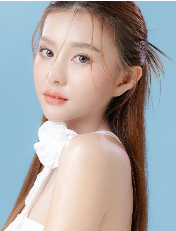 하늘색 배경 앞에서 어깨 너머로 돌아보는 여성 모델의 상반신.