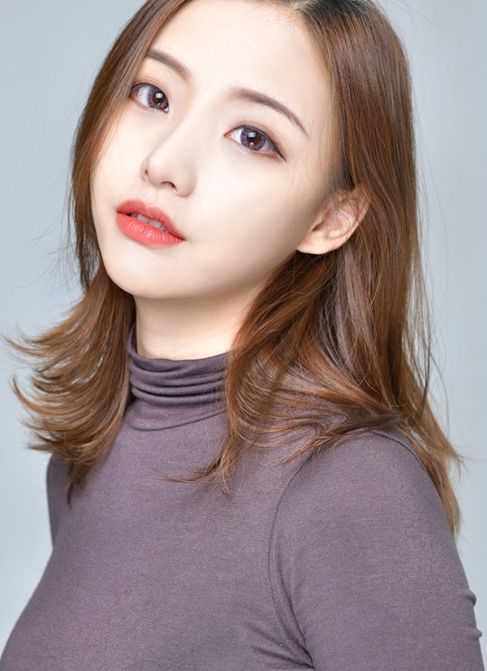 모브 컬러 터틀넥을 입은 여성이 몸을 살짝 틀어 정면을 바라보는 모습