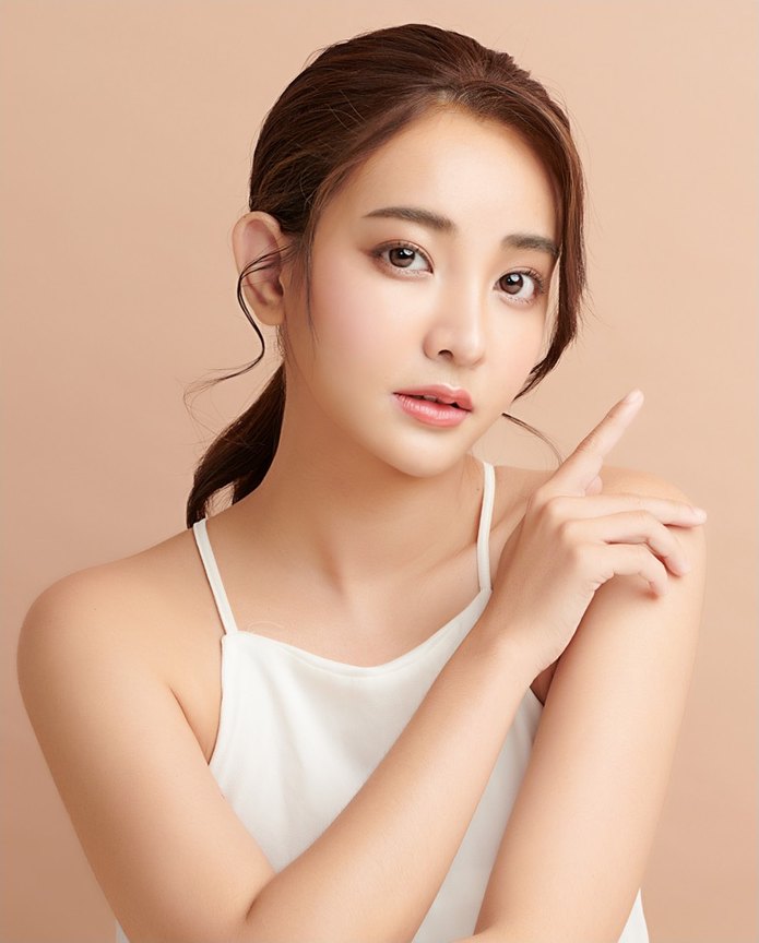 흰 캐미솔을 입은 여성이 검지를 얼굴 옆으로 들어 올린 채 정면을 바라보는 모습