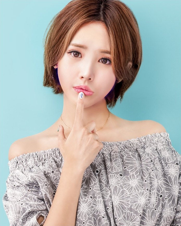 단발 브라운 헤어의 20대 한국인 여성 모델이 회색 아일렛 오프숄더 상의를 입고 검지로 아랫입술을 살짝 누르며 정면을 응시하는 상반신 사진