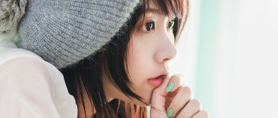 니트 비니를 쓴 여성이 손끝을 입가에 대고 옆을 바라보는 반측면 상반신