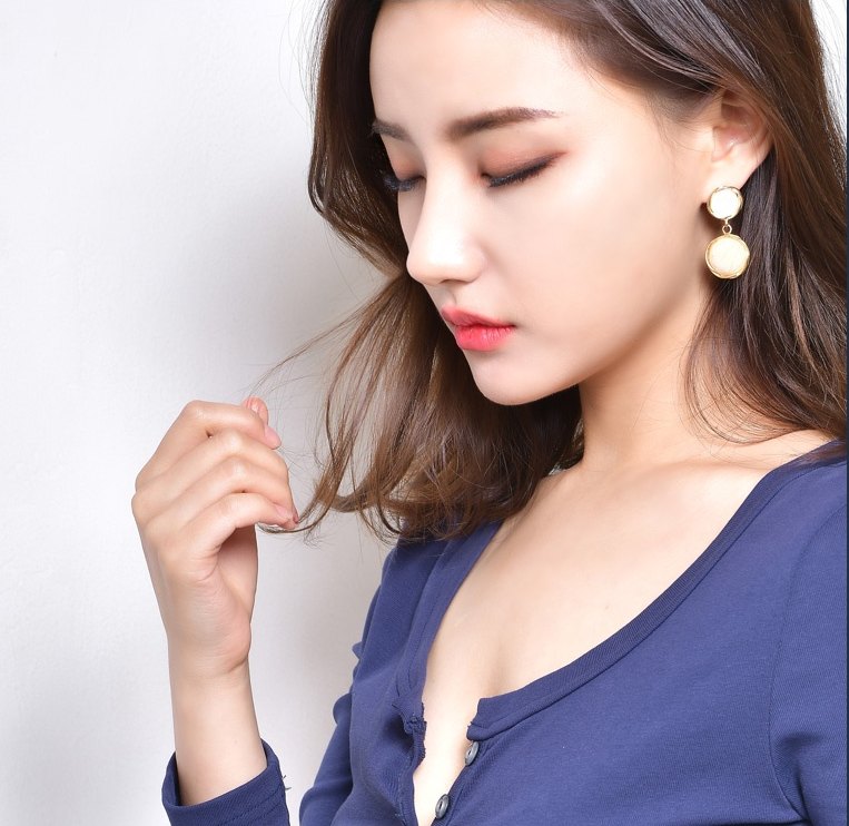 네이비 니트를 입은 여성이 고개를 숙이고 한 손으로 머리카락을 만지는 반신 컷