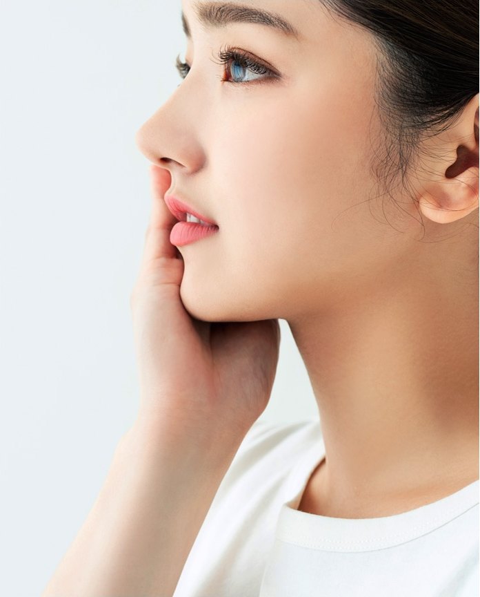 손끝을 입가에 댄 여성의 옆모습 클로즈업 — 코 라인이 화면 중앙에 놓인다