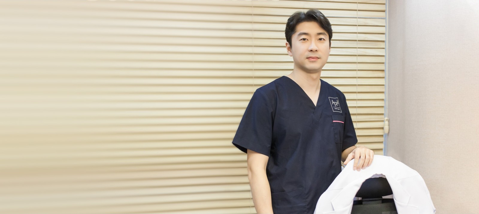 블라인드가 드리운 진료실 창가에 흰 가운을 손에 들고 선 송현석 원장